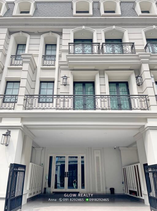 Front view of a residential building with white exterior, balconies, and large windows