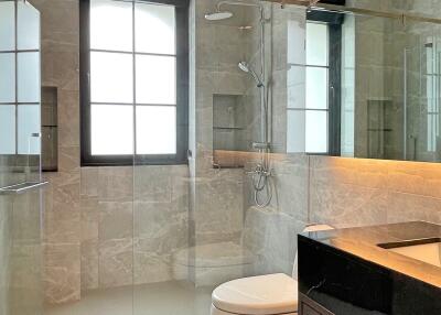 Modern bathroom with glass-enclosed shower, toilet, and vanity