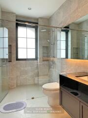 Modern bathroom with glass-enclosed shower, toilet, and vanity