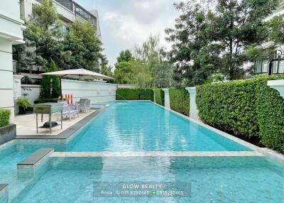 Outdoor swimming pool area with lush greenery and lounge seating