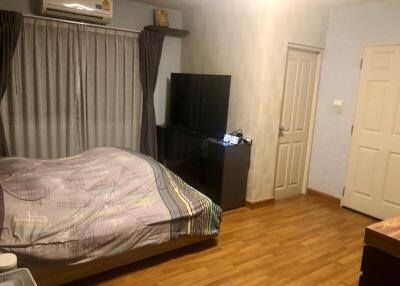 Cozy bedroom with wooden flooring featuring a bed, television, air conditioning, and curtained window