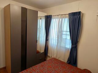 Bedroom with wardrobe and window with blue curtains