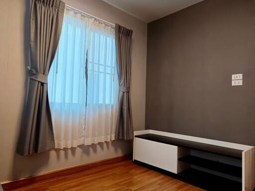 Bedroom with wooden flooring and window with curtains