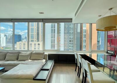 Modern living room with large windows, city view, and dining area