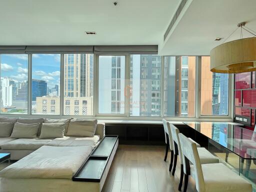 Modern living room with large windows, city view, and dining area