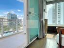 Balcony view towards high-rise buildings with glass door and curtains