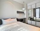 Modern, well-lit bedroom with a large bed, desk, chair, and mirrored wardrobe