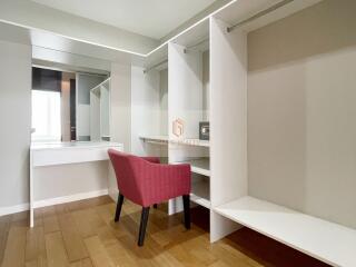 Walk-in closet with a vanity and red chair