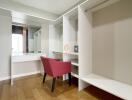 Walk-in closet with a vanity and red chair