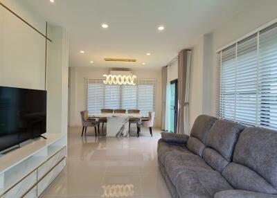 Spacious and modern living room with a large TV, dining area, and comfortable seating.