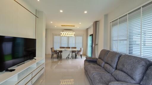 Spacious and modern living room with a large TV, dining area, and comfortable seating.