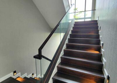 Modern staircase with glass railing and wall lighting