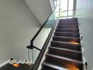 Modern staircase with glass railing and wall lighting