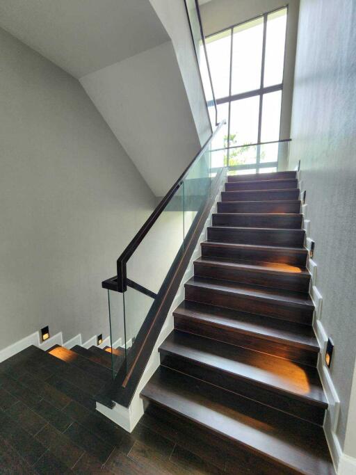 Modern staircase with glass railing and wall lighting
