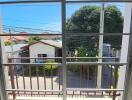 Balcony view with clear blue sky, trees, and neighborhood houses