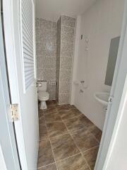 Clean bathroom with tiled walls and floors, including a toilet, sink, and shower