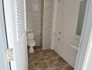 Clean bathroom with tiled walls and floors, including a toilet, sink, and shower