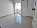 Empty bedroom with a door and a window leading to a balcony