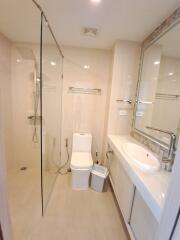 Modern bathroom with glass shower, toilet, sink, and vanity