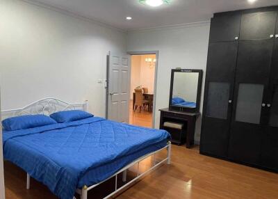 Bedroom with blue bedspread, white walls, and dark wardrobe