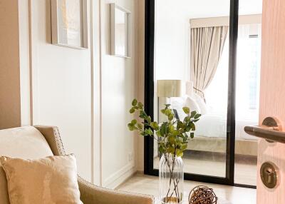 Cozy living room with armchair, table, and a view into a bedroom