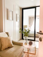 Cozy living room with armchair, table, and a view into a bedroom