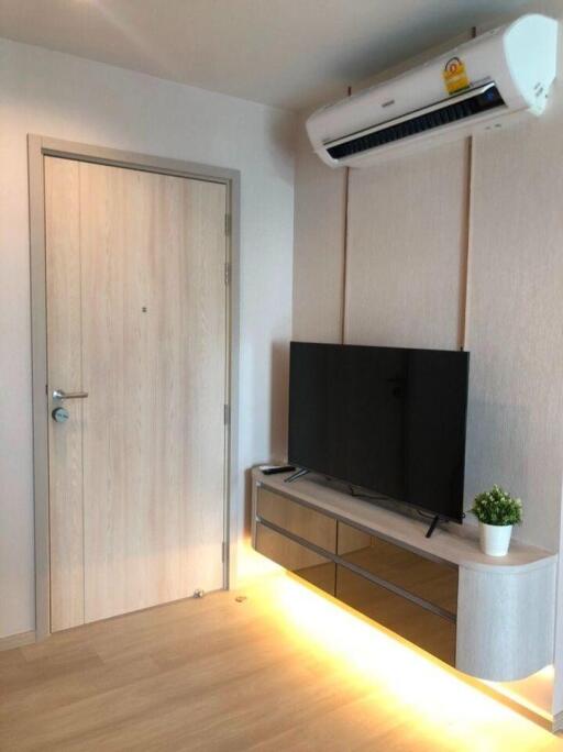 Modern living room with air conditioner, TV, and wooden furniture.