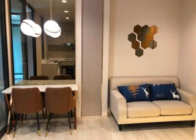 Modern living room and dining area with white sofa, decorative pillows, wooden dining table, and modern light fixtures.