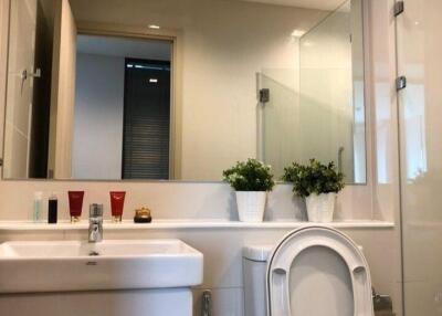 Modern bathroom with large mirror, sink, and toilet