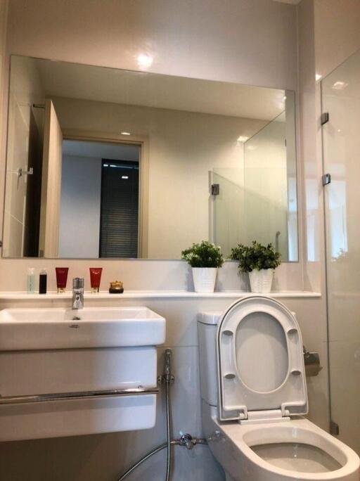 Modern bathroom with large mirror, sink, and toilet