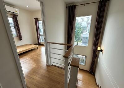 View of a bright hallway leading into a bedroom with wooden flooring