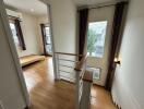 View of a bright hallway leading into a bedroom with wooden flooring