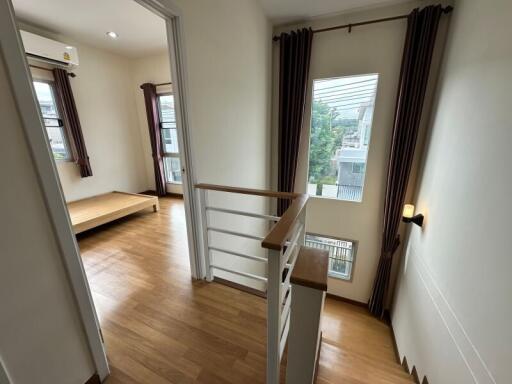 View of a bright hallway leading into a bedroom with wooden flooring