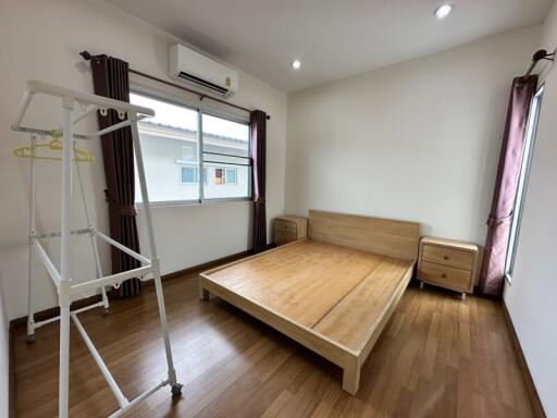 A modern minimalist bedroom with wooden furniture and large windows