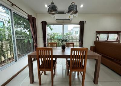 Dining room with wooden table and chairs, large windows, and air conditioning