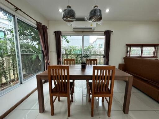 Dining room with wooden table and chairs, large windows, and air conditioning