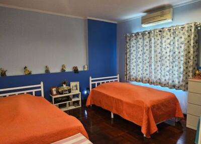 Two beds in a brightly decorated bedroom with hardwood floors and blue accent wall