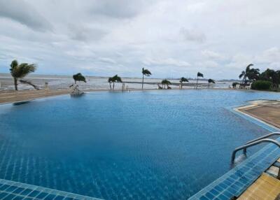 View of a large outdoor swimming pool with ocean in the background