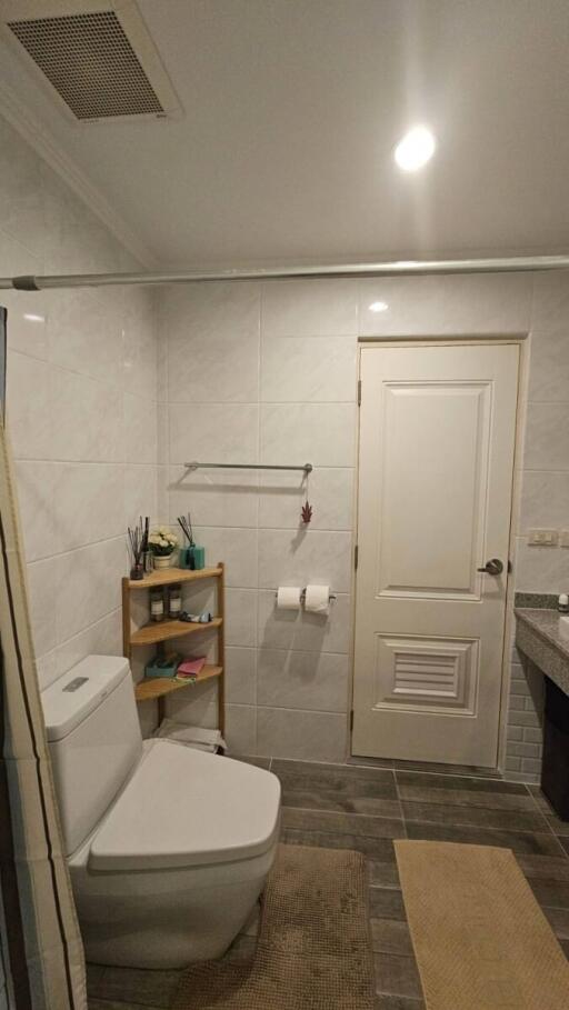 Bathroom with a white toilet, shelving, and a sink