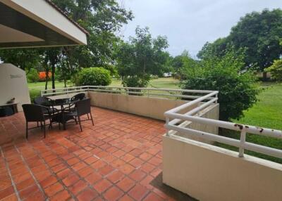 Outdoor patio with table and chairs, overlooking a green area