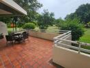 Outdoor patio with table and chairs, overlooking a green area