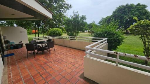 Outdoor patio with table and chairs, overlooking a green area