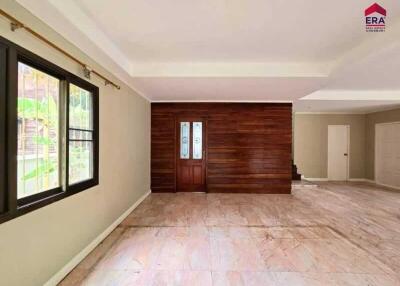 Spacious living room with large window and wooden wall feature