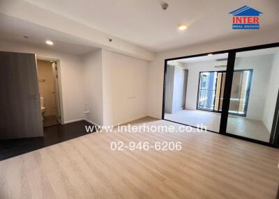 Spacious living room with wooden flooring and large glass doors leading to a balcony.