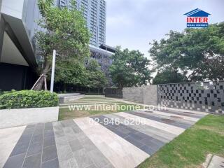 Outdoor area with modern pavement, greenery, and a tall building.