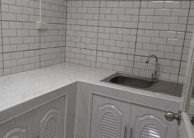 Small modern kitchen with white tile backsplash and cabinets