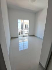 Empty bedroom with shiny tiled floor and balcony access