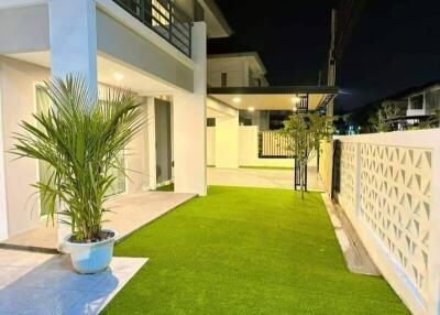 Side view of a modern house with artificial turf and potted plants