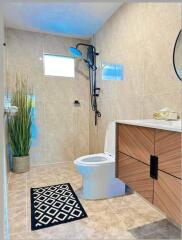 Modern bathroom with wooden vanity, potted plant, and walk-in shower