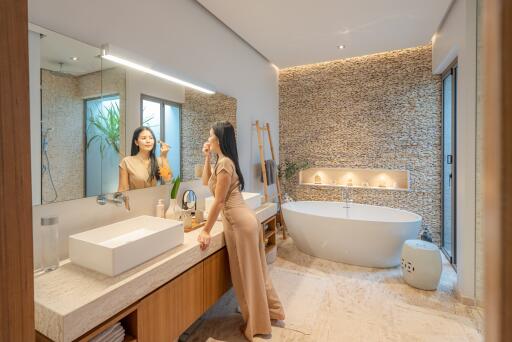 Modern bathroom with vanity, bathtub, and decorative stone wall